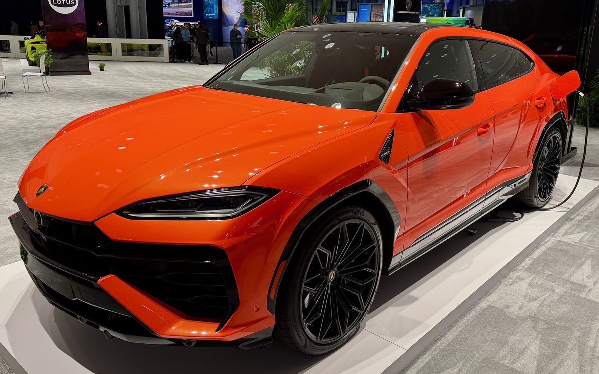 Orangefarbener Lamborghini Urus SE auf einem Messestand, Frontansicht von schräg vorn